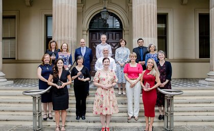 A group of people standing on the steps of a building holding awards.